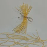 Fideos de pasta amarilla atados con cuerda, sobre fondo blanco, ideales para recetas de cocina italiana.