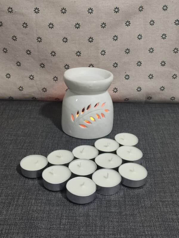 Difusor de cerámica blanca con diseño de hojas, acompañado de velas tipo té. Fondo textil con estampado de flores. Ideal para aromaterapia y ambientación.