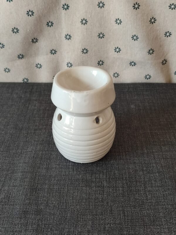 Vaso de cerámica blanca con diseño estriado, ideal para aromatizantes o velas, sobre fondo textil gris.