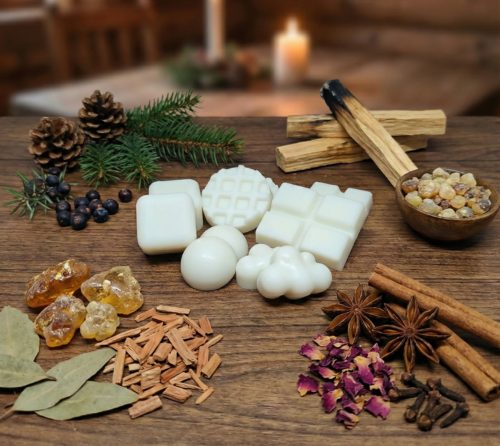 Composición de estilo rústico con tabletas de wax melts de cera de soja blanca. La imagen incluye piñas de pino, ramas de canela atadas y madera natural, representando aromas cálidos de bosque, palo santo y sándalo para la relajación.