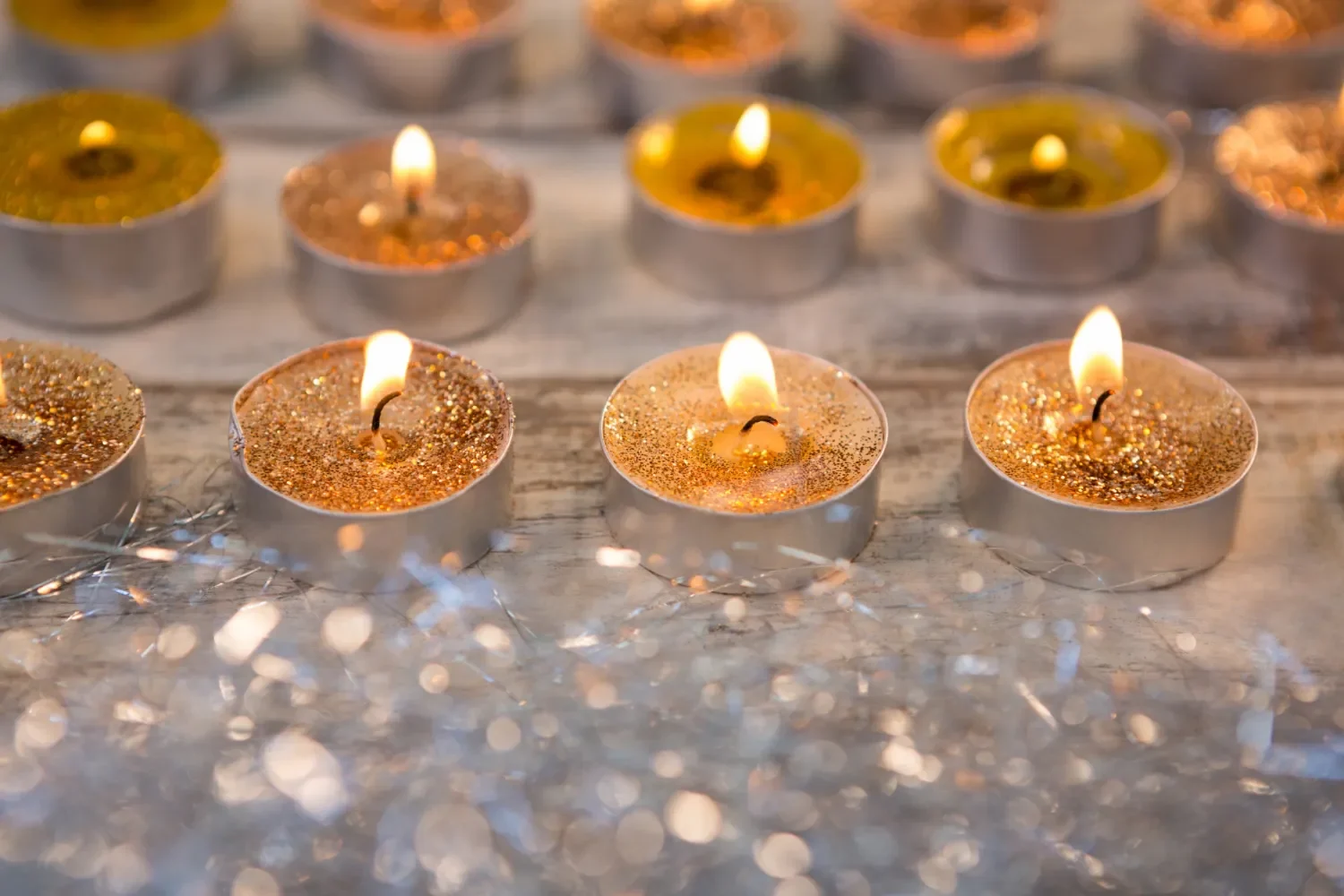 Velas decorativas con brillo encendidas sobre una superficie de madera, creando un ambiente cálido y festivo.
