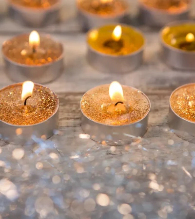 Velas decorativas con brillo encendidas sobre una superficie de madera, creando un ambiente cálido y festivo.